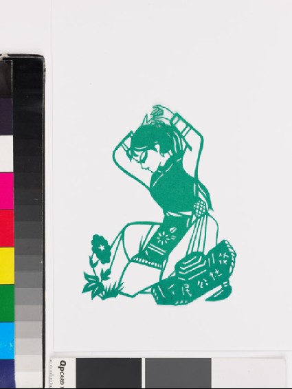 Girl in national minority costume kneeling by a flowerfront