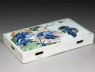 Blue-and-white tile with a landscape on one side and flowers on the other (oblique)